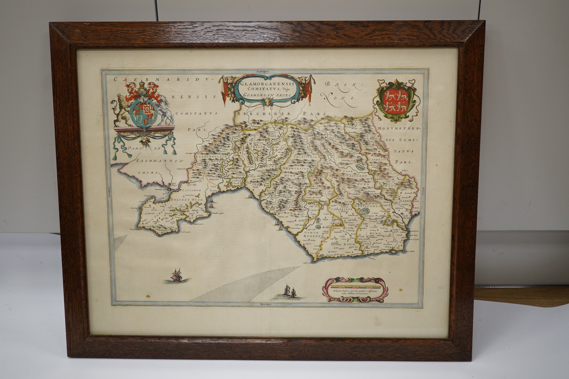 An oak cased collection of rifle and shooting medals disguised as a framed map of Glamorganshire, containing hallmarked silver medals engraved to the awardees, cloth badges for Glamorgan Rifle Association, bronze rifle a